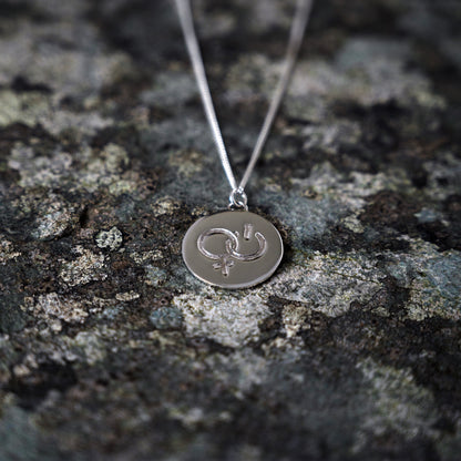 Silver pendant with girl power symbol, on slate background