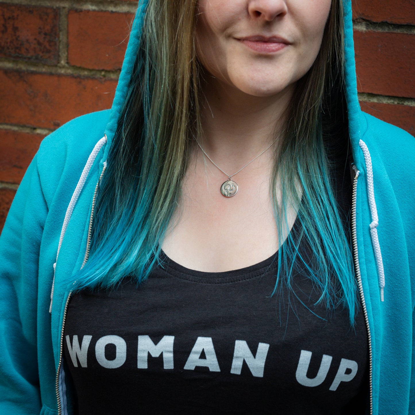 Silver pendant with girl power symbol, on model wearing Woman Up top