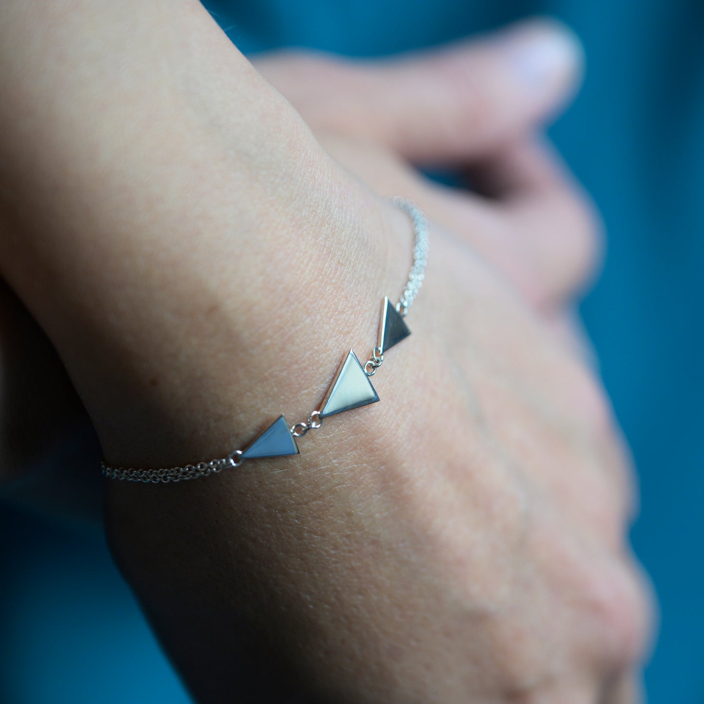 Silver bracelet with three triangles on model's wrist