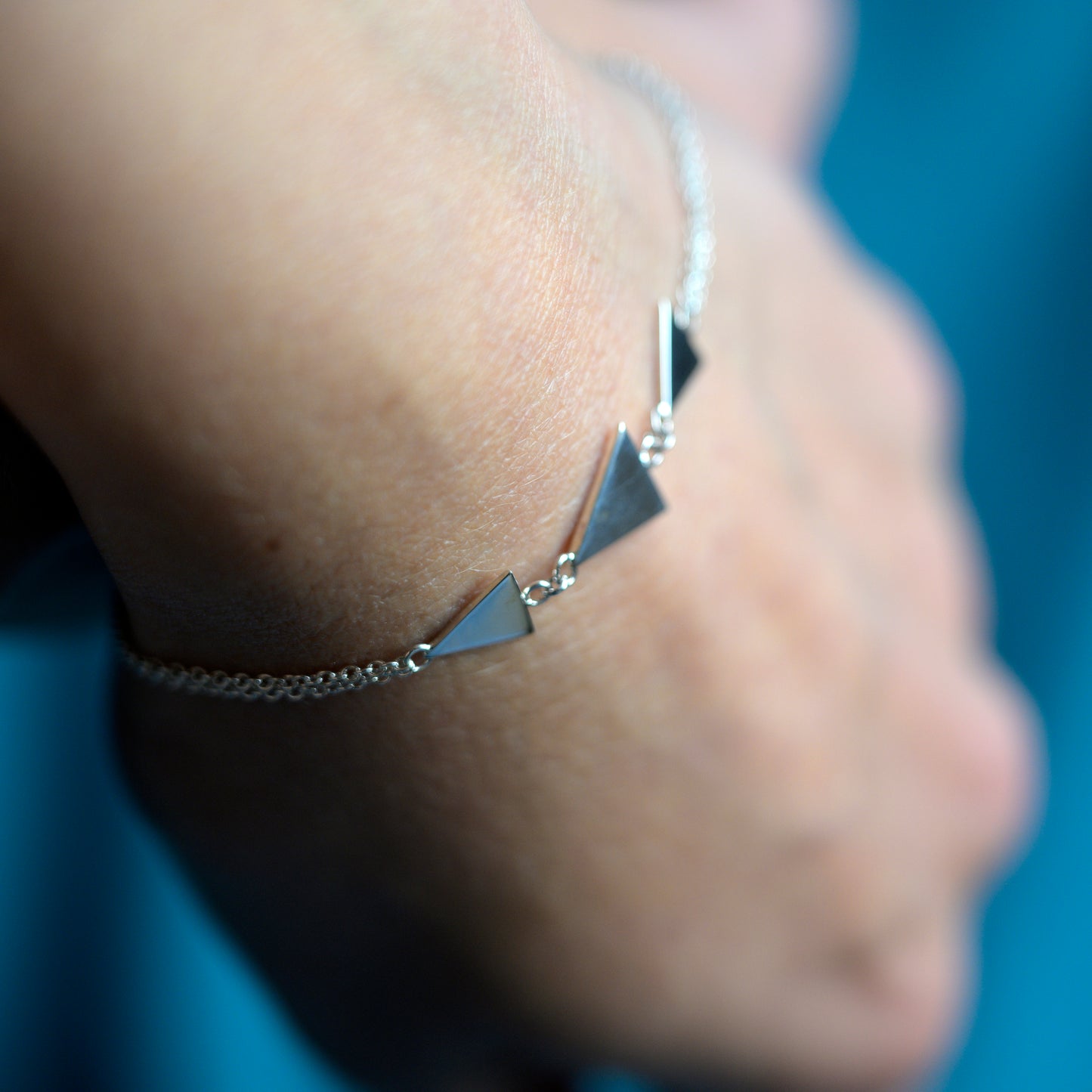 Close up of silver bracelet with three triangles on model's wrist