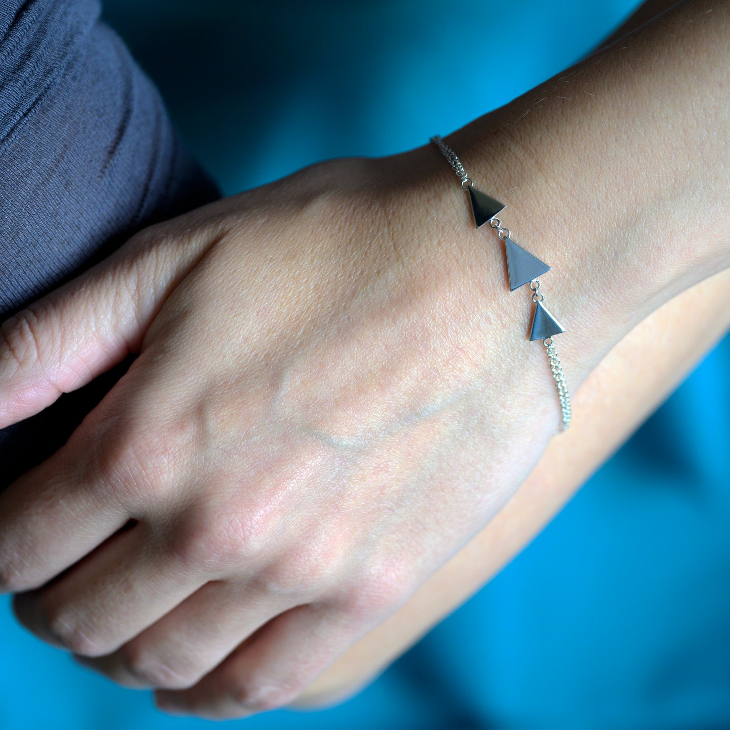 Silver bracelet with three triangles on model's wrist